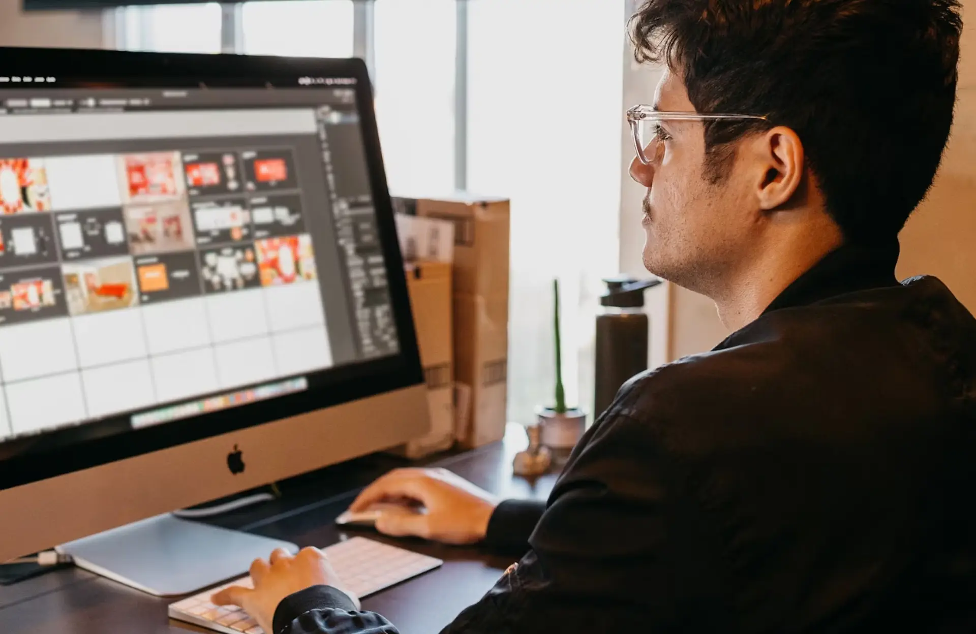 FX Productions Canada A person wearing glasses works at a desktop computer, editing images on a large monitor in a well-lit office space. Toronto Video Production Company