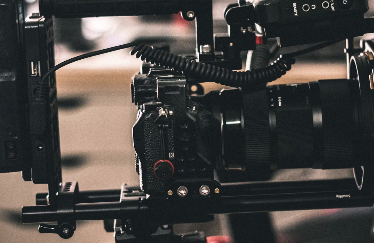 FX Productions Canada Close-up view of a professional digital camera mounted on a stabilizing rig, with a coiled cable attached, in an indoor setting. Toronto Video Production Company