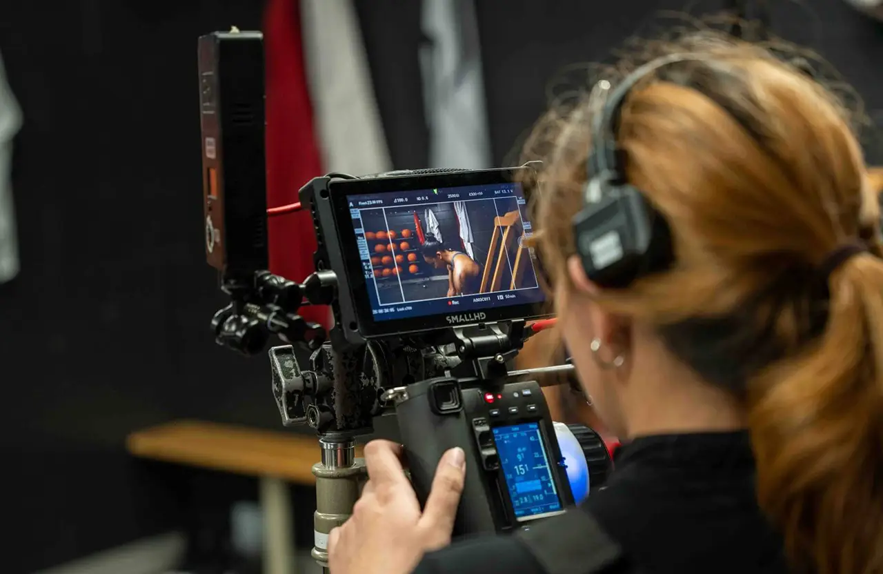 FX Productions Canada A person wearing headphones operates a camera rig with a monitor displaying a close-up shot of a person’s legs and a basketball. Toronto Video Production Company