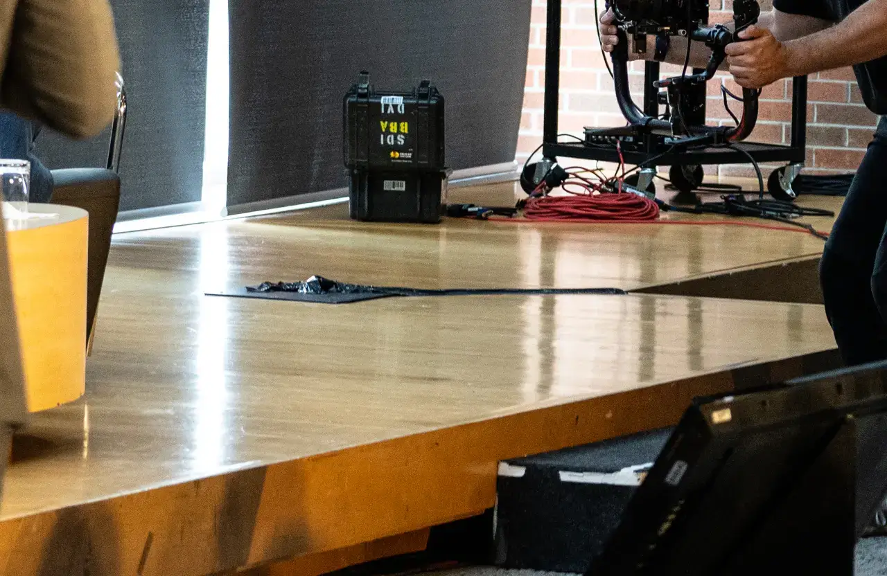 FX Productions Canada A thick black cable runs across a wooden stage floor, with camera equipment and a coiled red cable in the background—capturing the behind-the-scenes of corporate video production in Toronto. Toronto Video Production Company