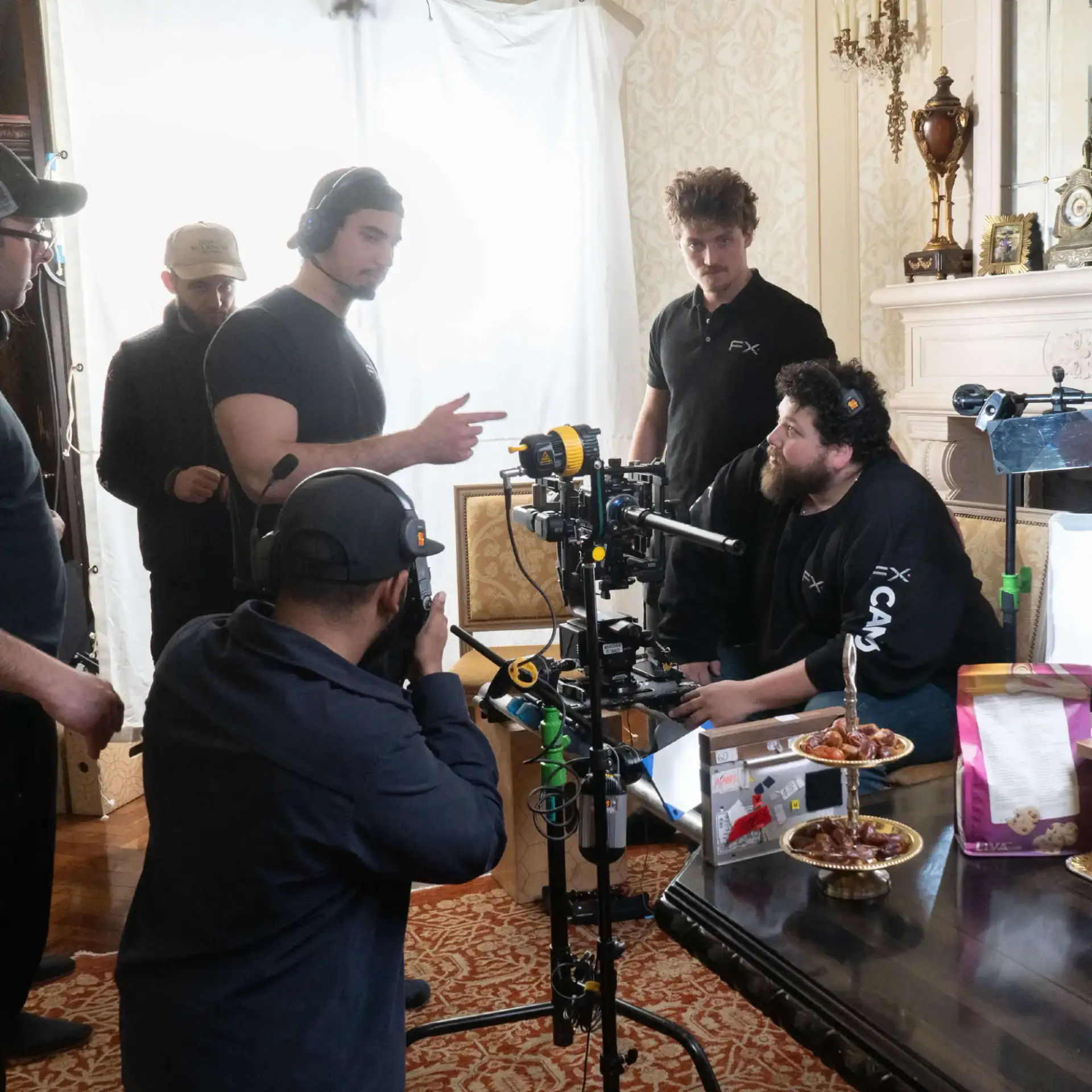 FX Productions Canada A film crew sets up camera equipment and discusses a scene in a room with ornate decor, food on the table, and lighting equipment visible. Toronto Video Production Company