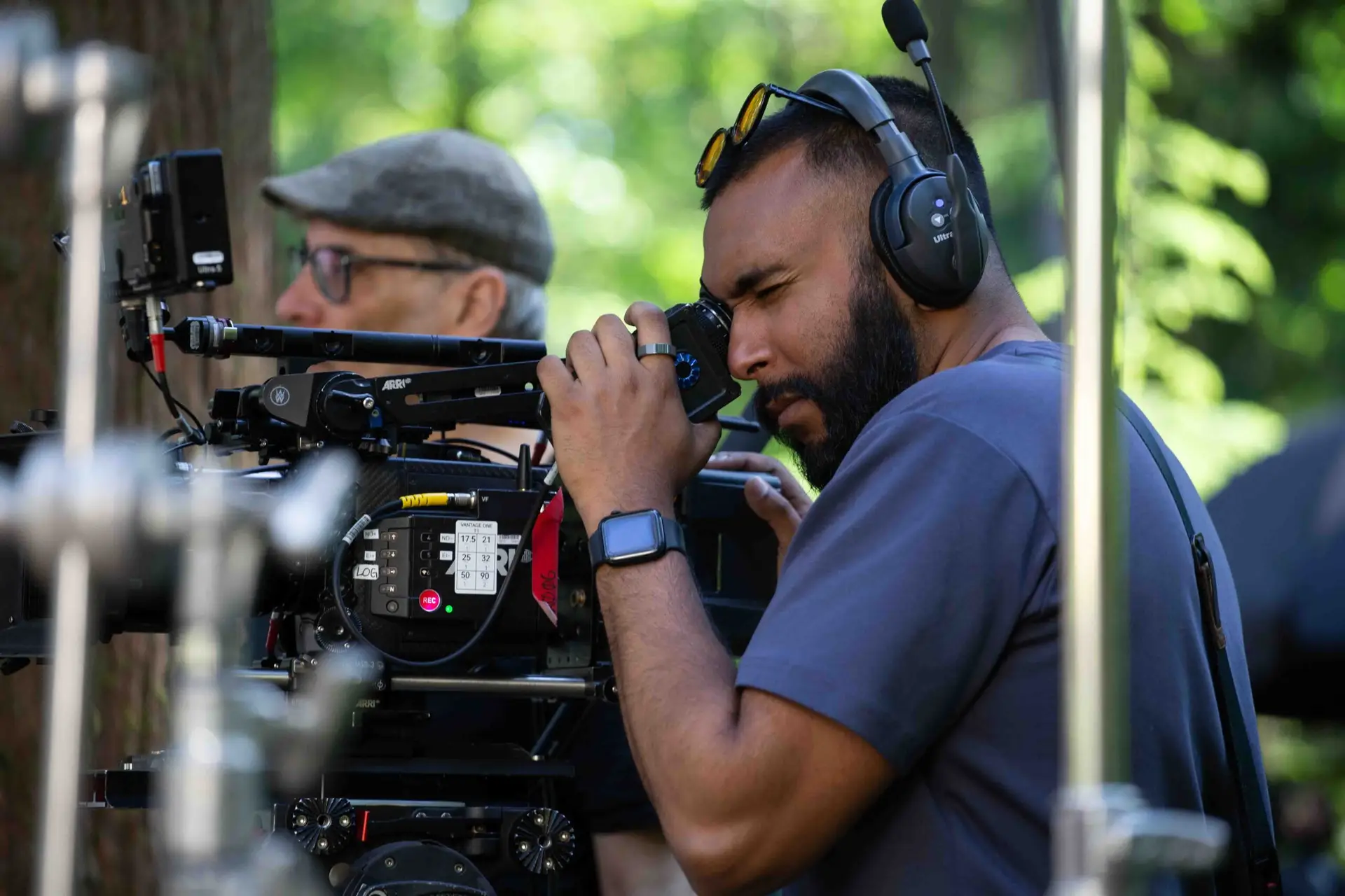 FX Productions Canada A man operates a professional video camera outdoors, wearing headphones and a smartwatch, with another person in the background. Toronto Video Production Company