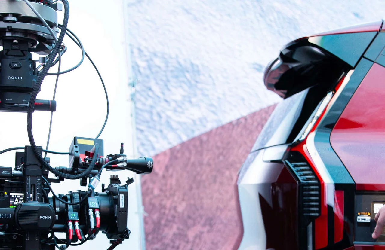 FX Productions Canada A professional camera rig films the rear section of a red and black car, with the car’s taillight and spoiler in view against a light background, showcasing how video production competes on a global stage. Toronto Video Production Company