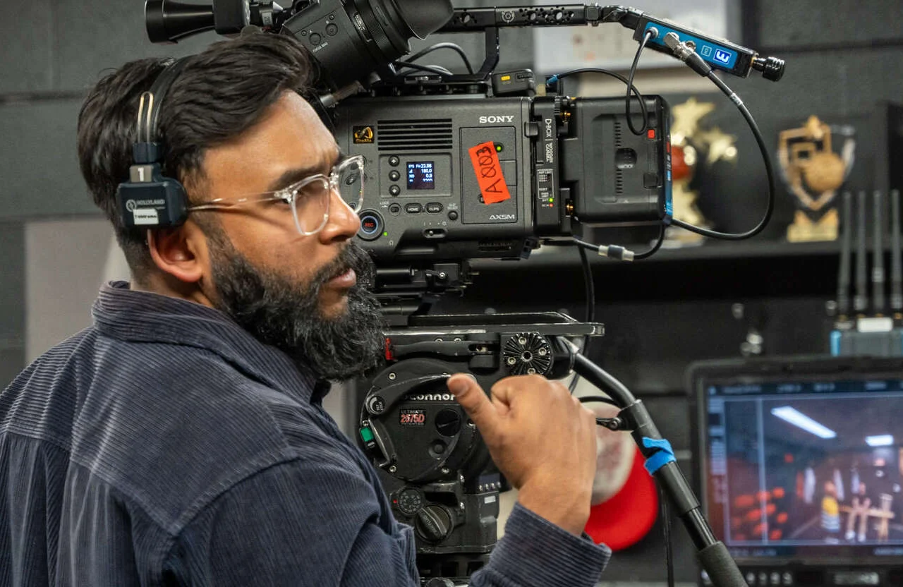 FX Productions Canada A man wearing headphones operates a professional Sony video camera on a tripod in an indoor studio setting, capturing footage for basic to premium video production projects. Toronto Video Production Company