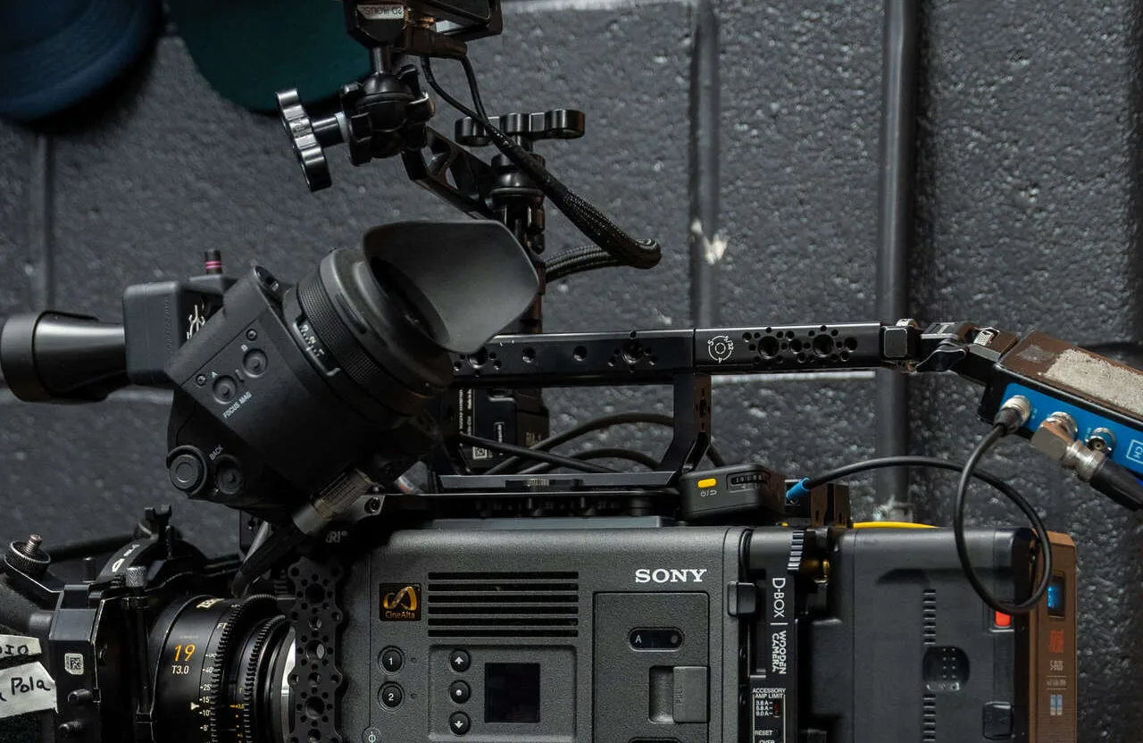 FX Productions Canada A close-up of a professional Sony video camera rig with various attachments and cables, positioned against a gray textured wall—a powerful setup perfect for any video production company seeking high-quality results. Toronto Video Production Company
