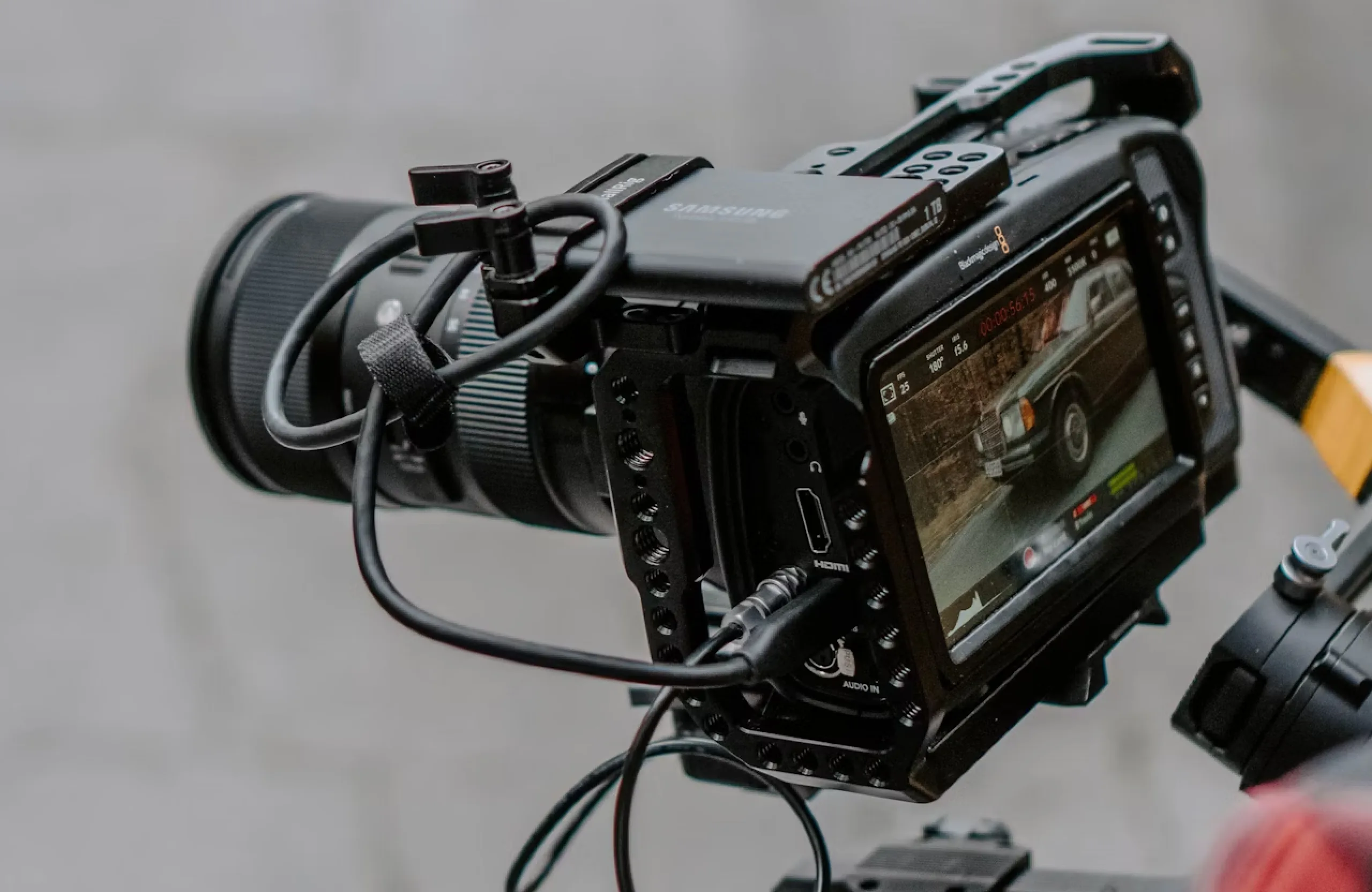 FX Productions Canada A professional video camera on a tripod records a vintage car, visible on the camera’s monitor screen, with various cables connected and controls on the side—an ideal setup for those curious about how much professional video production costs. Toronto Video Production Company